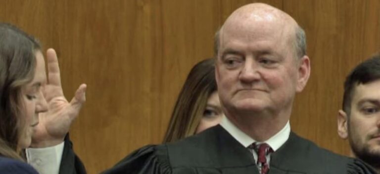 Judge James McClusky being sworn in, right hand raised, during his official ceremony to begin his new term on the New York State Supreme Court.