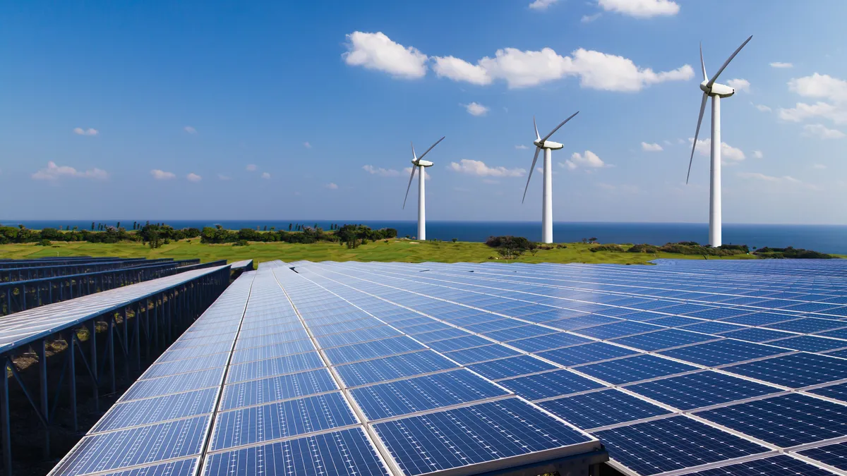 Windmills and solar panels near the Lake Ontario shoreline under a cloudy Upstate New York sky.