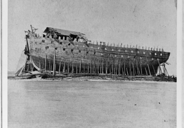 Historic photograph of the unfinished USS New Orleans, a massive War of 1812 ship-of-the-line, resting under its deteriorating shiphouse at Sackets Harbor, New York.
