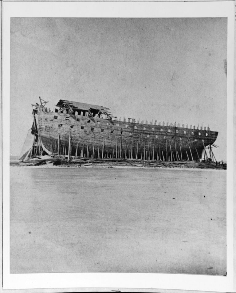 Historic photograph of the unfinished USS New Orleans, a massive War of 1812 ship-of-the-line, resting under its deteriorating shiphouse at Sackets Harbor, New York.