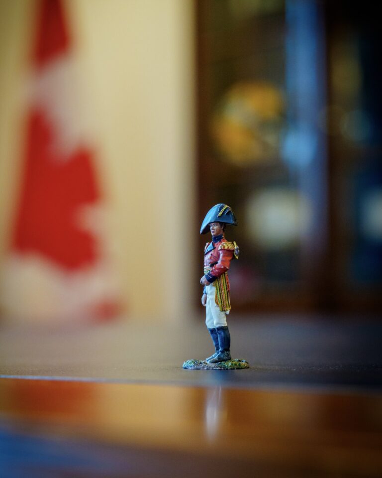 Red-coated figurine of Major-General Sir Isaac Brock on Mark Carney’s desk, with a blurred Canadian flag behind it.