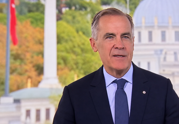 Digitally enhanced broadcast screen capture of Mark Carney speaking in a dark suit and blue tie, supplied by Hans Wilder / Digital Media USA.