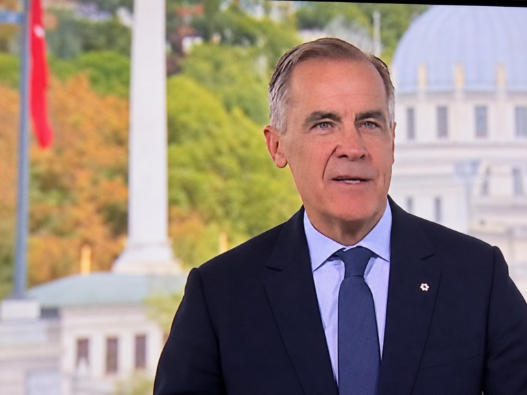 Digitally enhanced broadcast screen capture of Mark Carney speaking in a dark suit and blue tie, supplied by Hans Wilder / Digital Media USA.