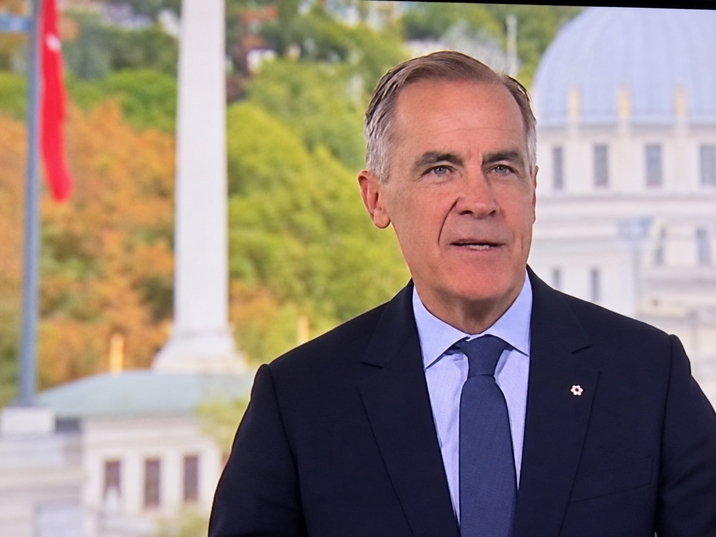 Digitally enhanced broadcast screen capture of Mark Carney speaking in a dark suit and blue tie, supplied by Hans Wilder / Digital Media USA.