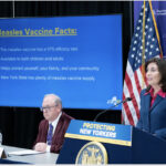 Governor Kathy Hochul speaks beside a display of measles vaccine facts during a New York State public health briefing.